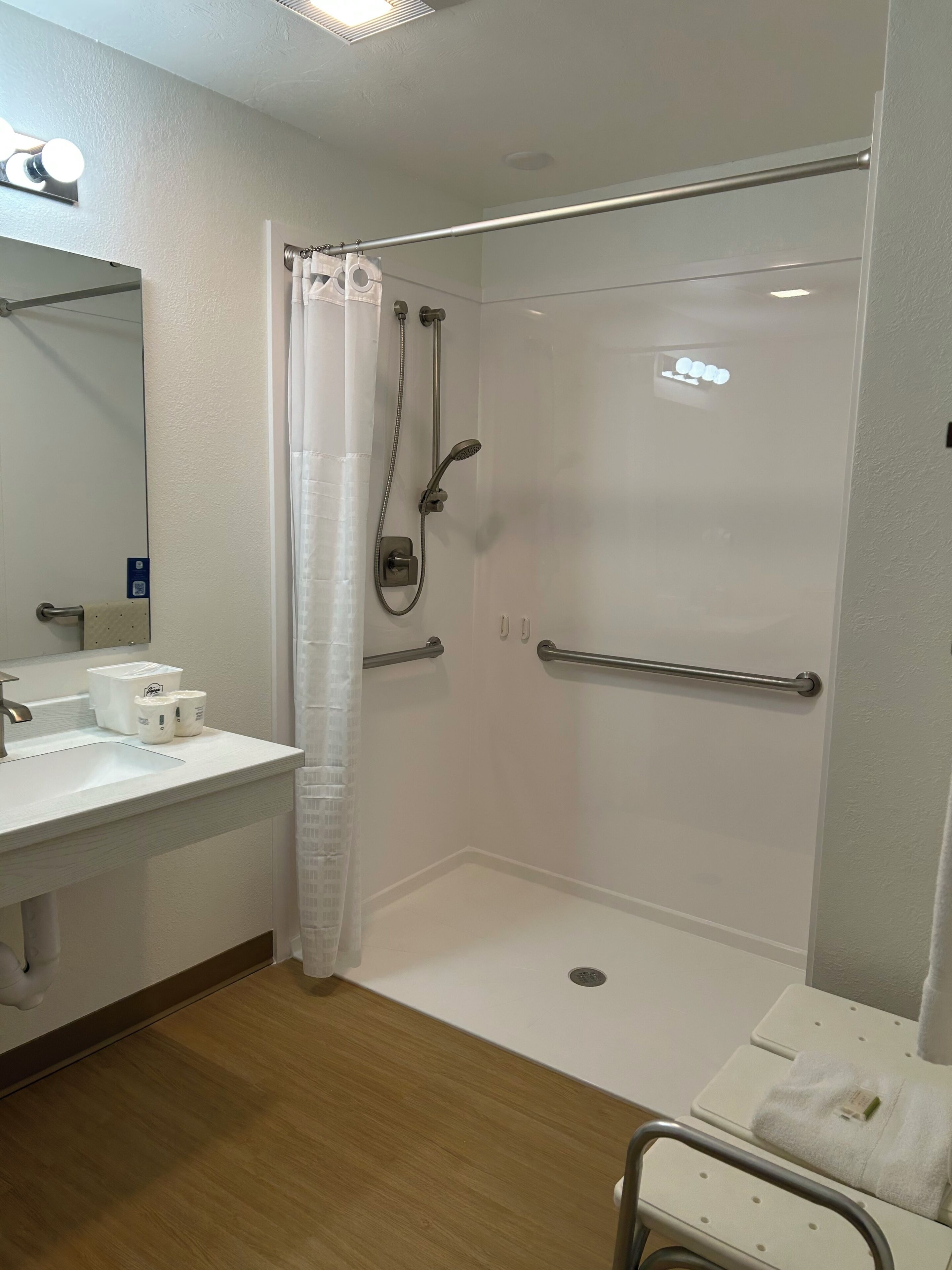 A modern bathroom with a shower, a sink, and a mirror.