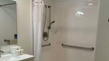 Un bagno moderno con doccia, lavandino e specchio.