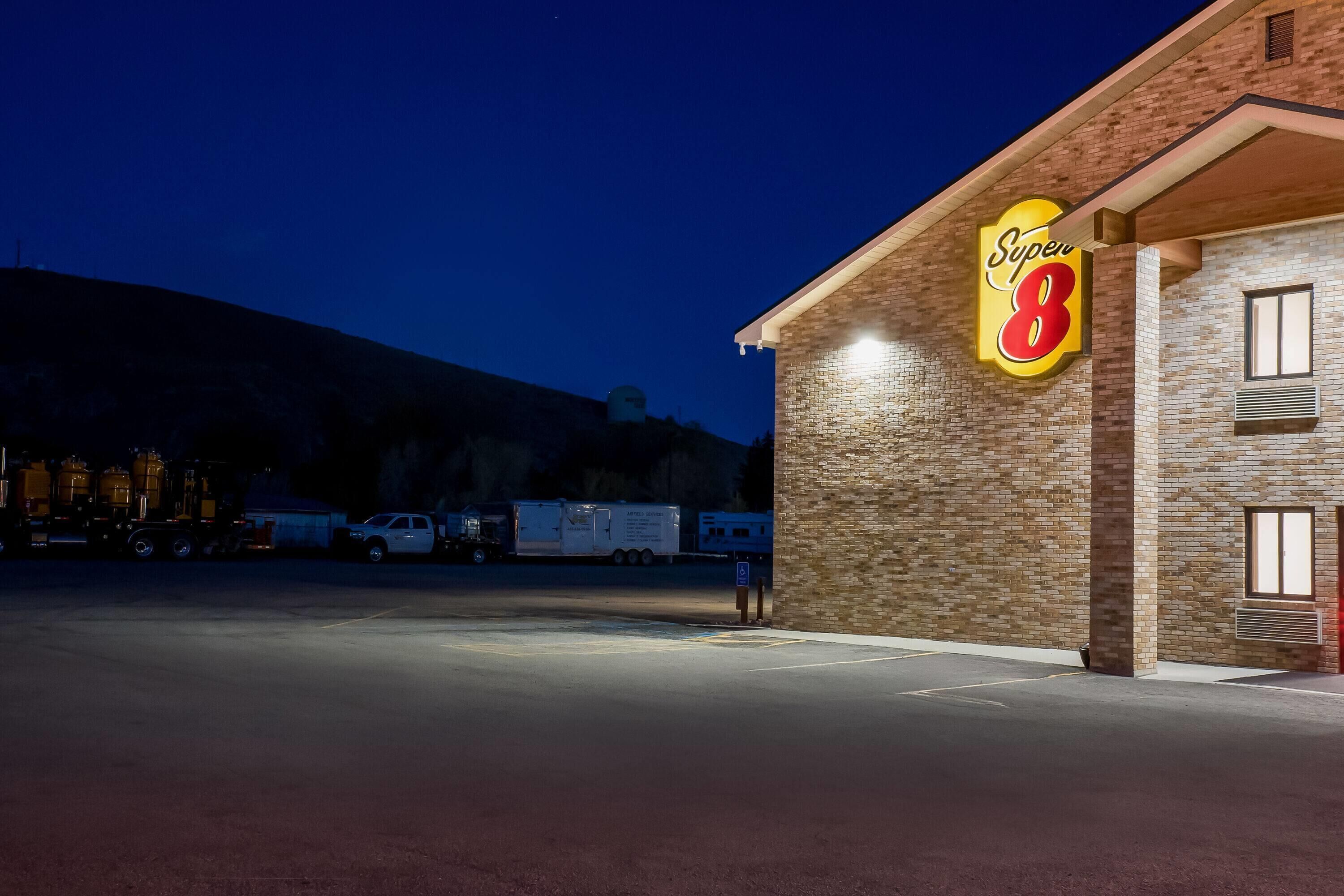 A Super 8 hotel with a brick facade, a large illuminated sign, and a parking lot.