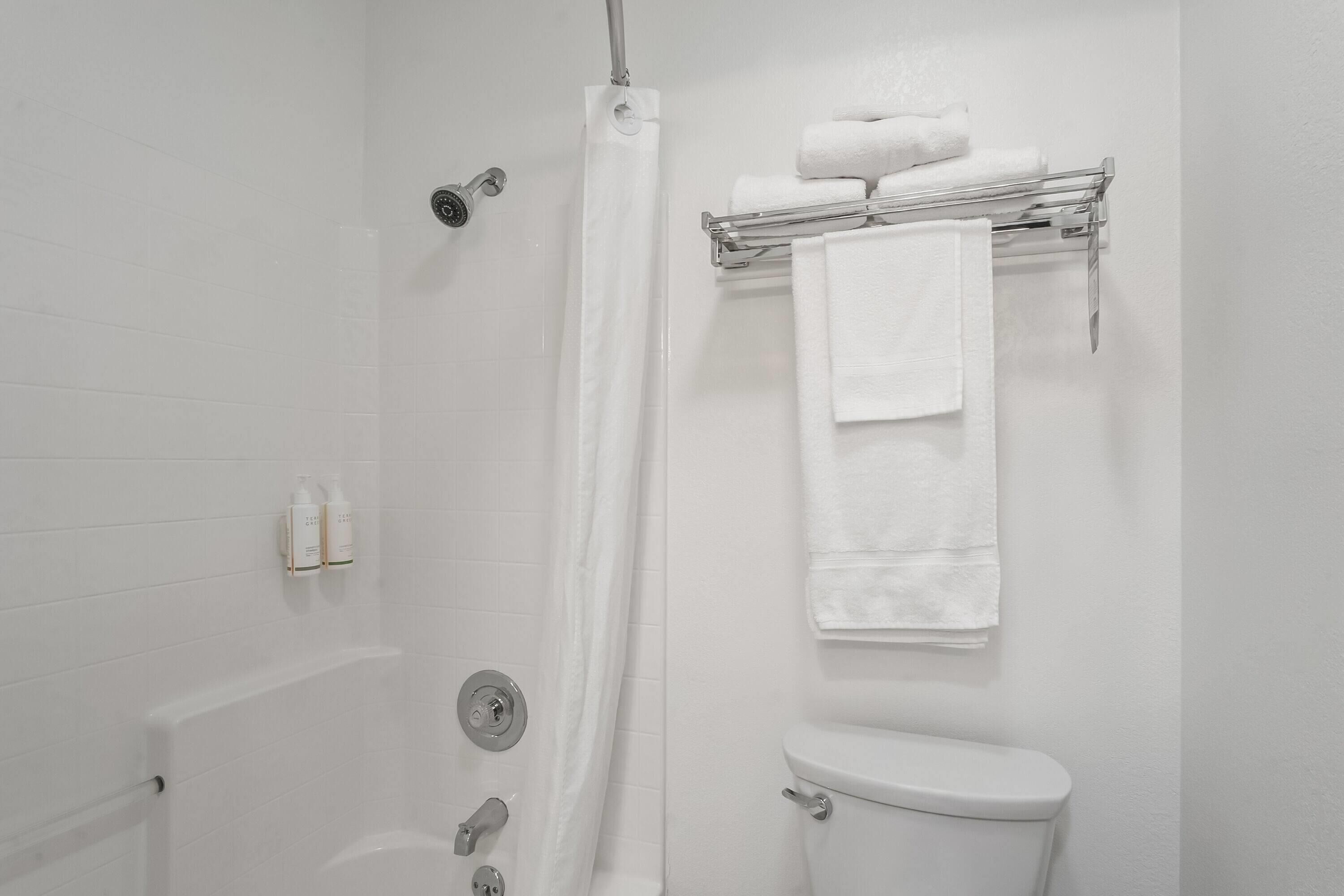 A bathroom with a white toilet, a shower with a glass door, and a towel rack with folded towels.