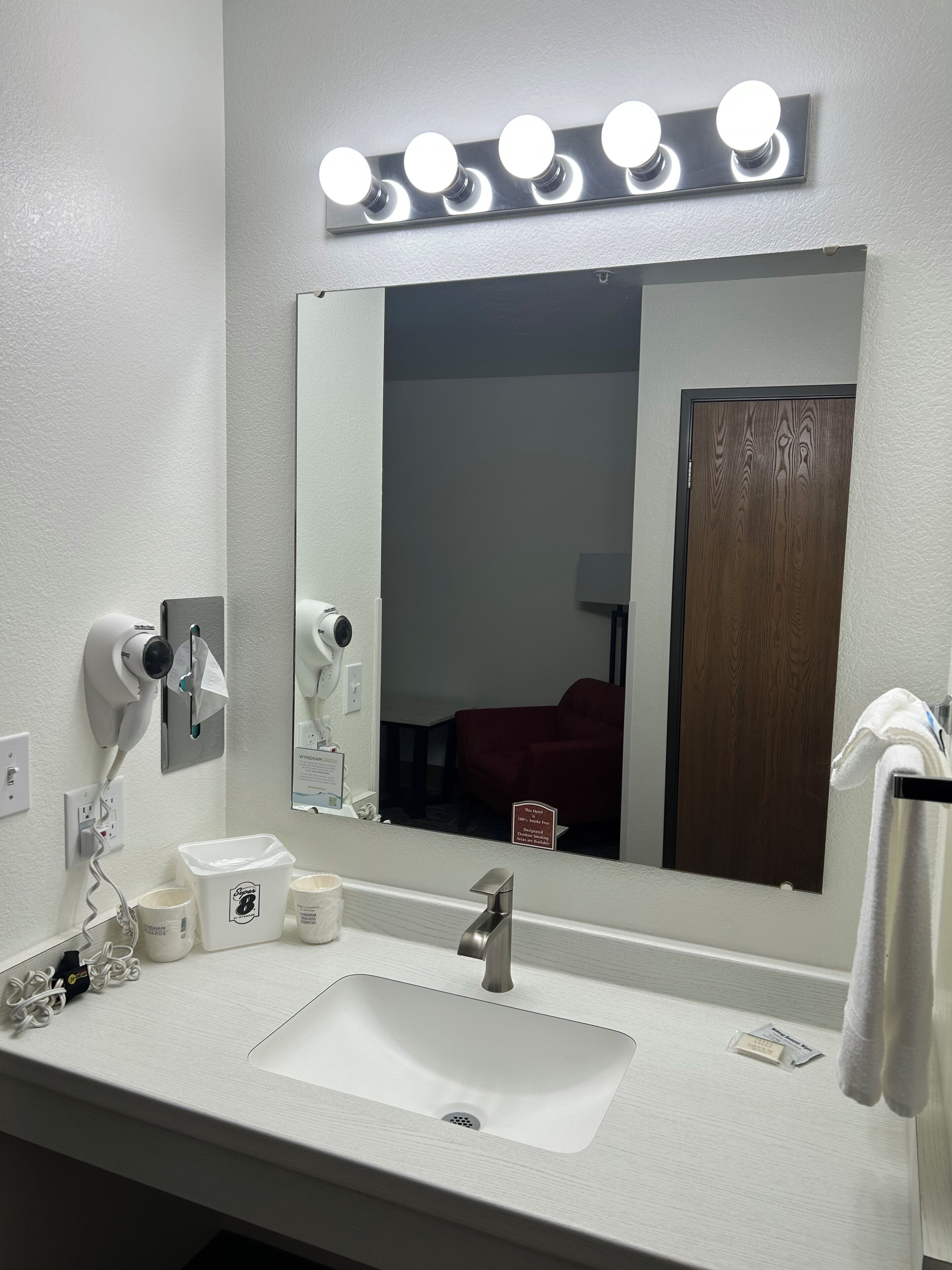 Une salle de bain d’hôtel avec un grand miroir, un lavabo et un sèche-cheveux.