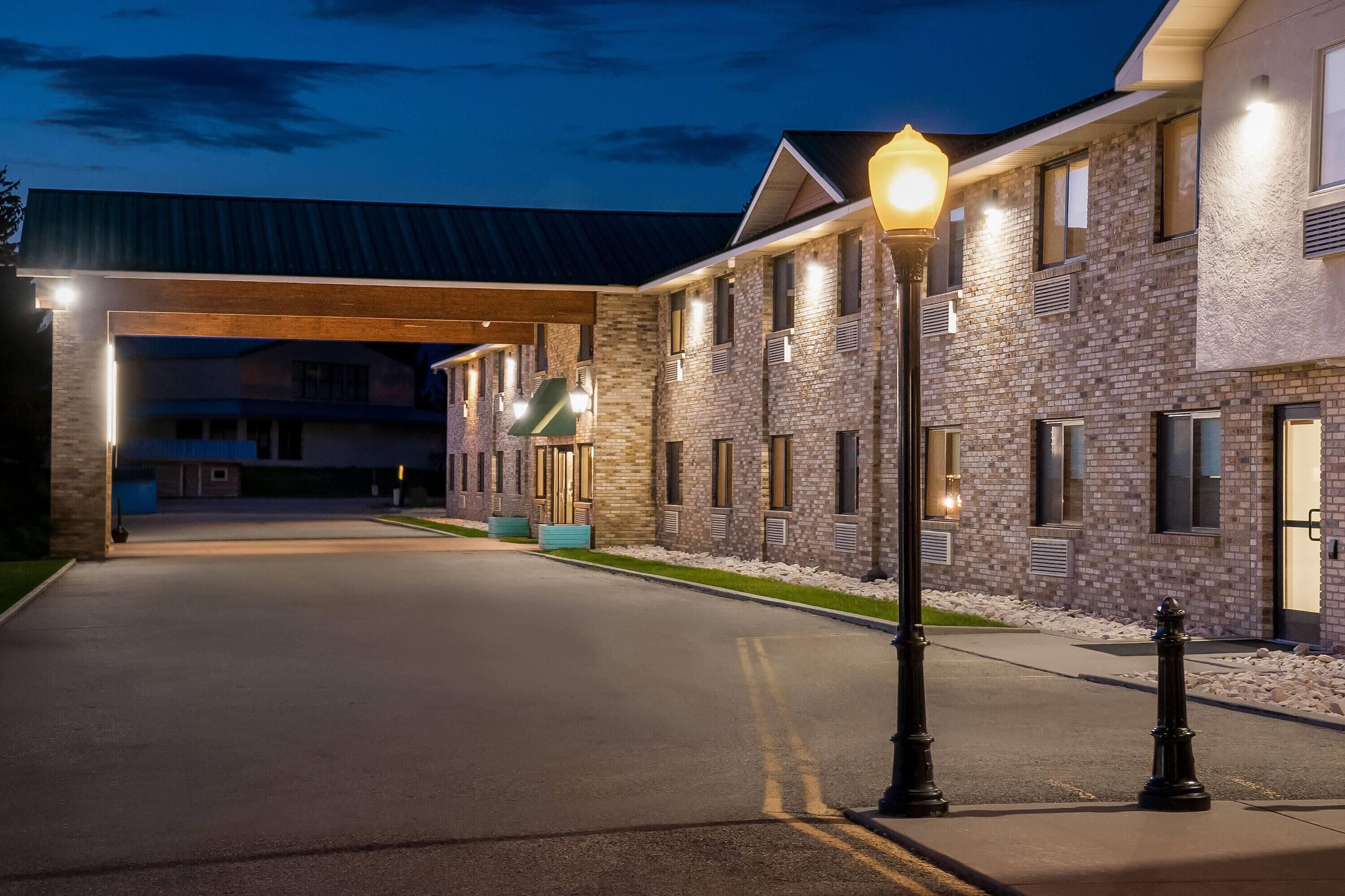A hotel entrance with a covered walkway, brick exterior, and street lamps.