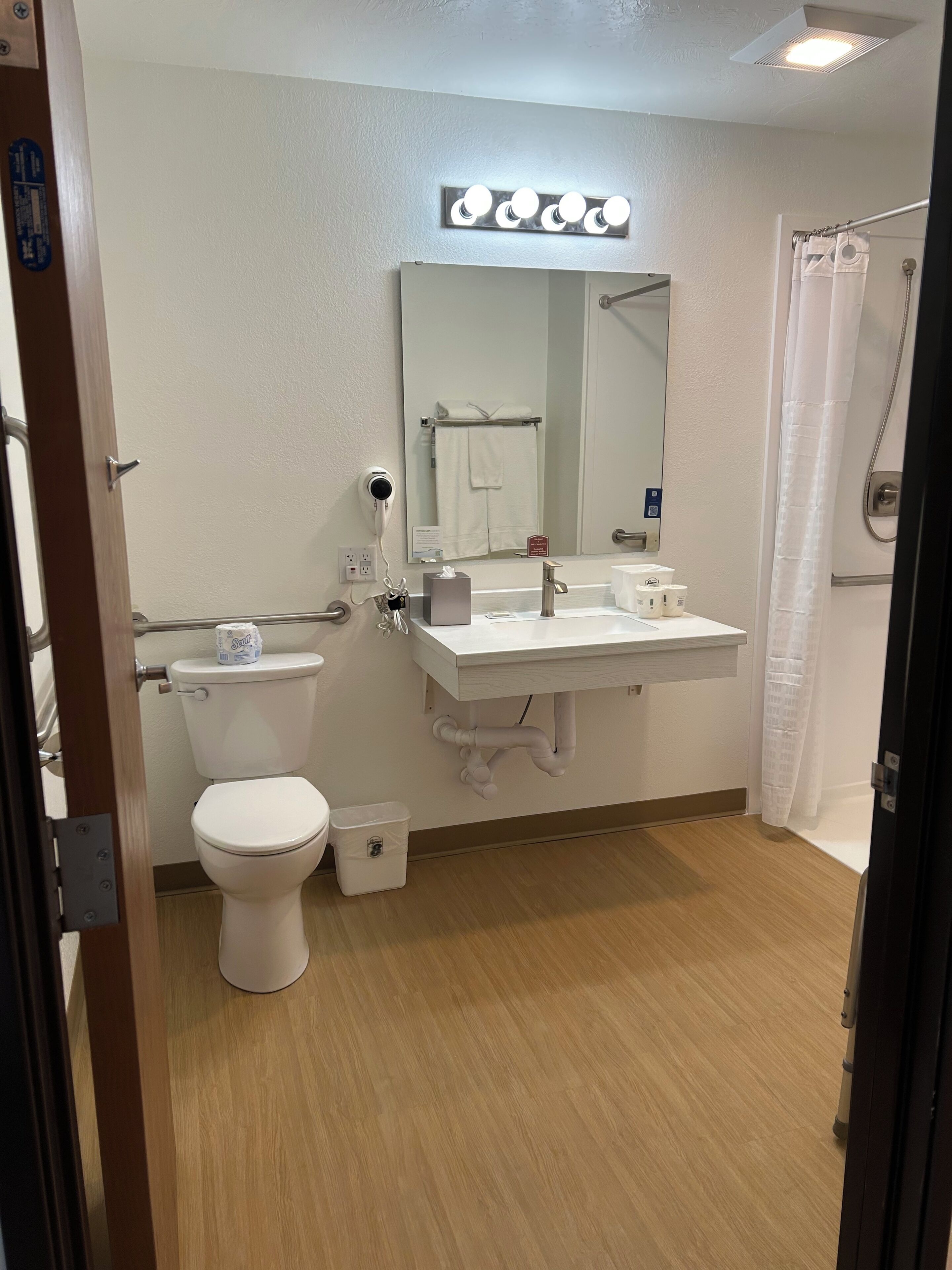 A bathroom with a toilet, sink, mirror, and shower curtain.