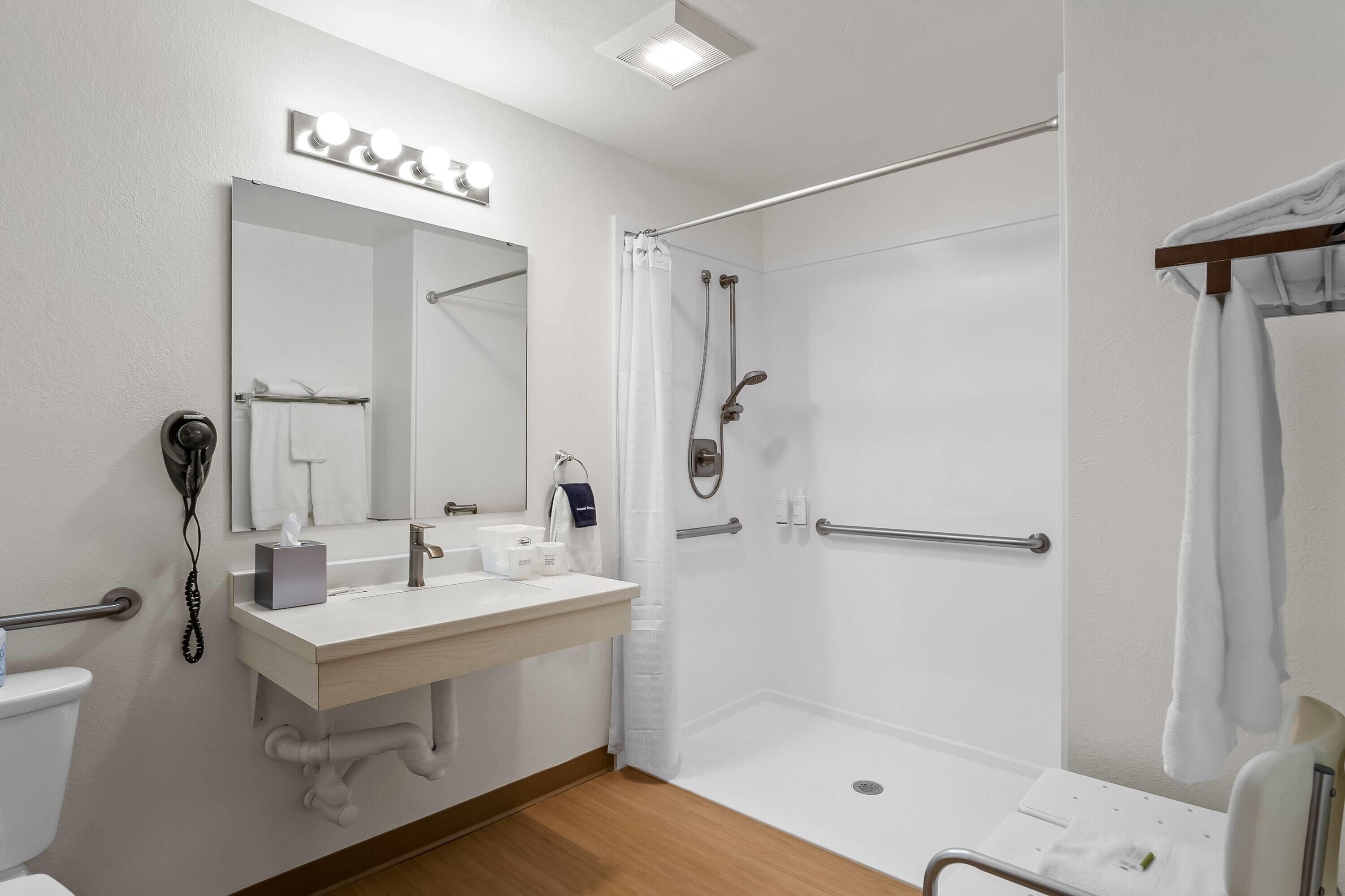 Un baño moderno con tocador, espejo, ducha e inodoro.