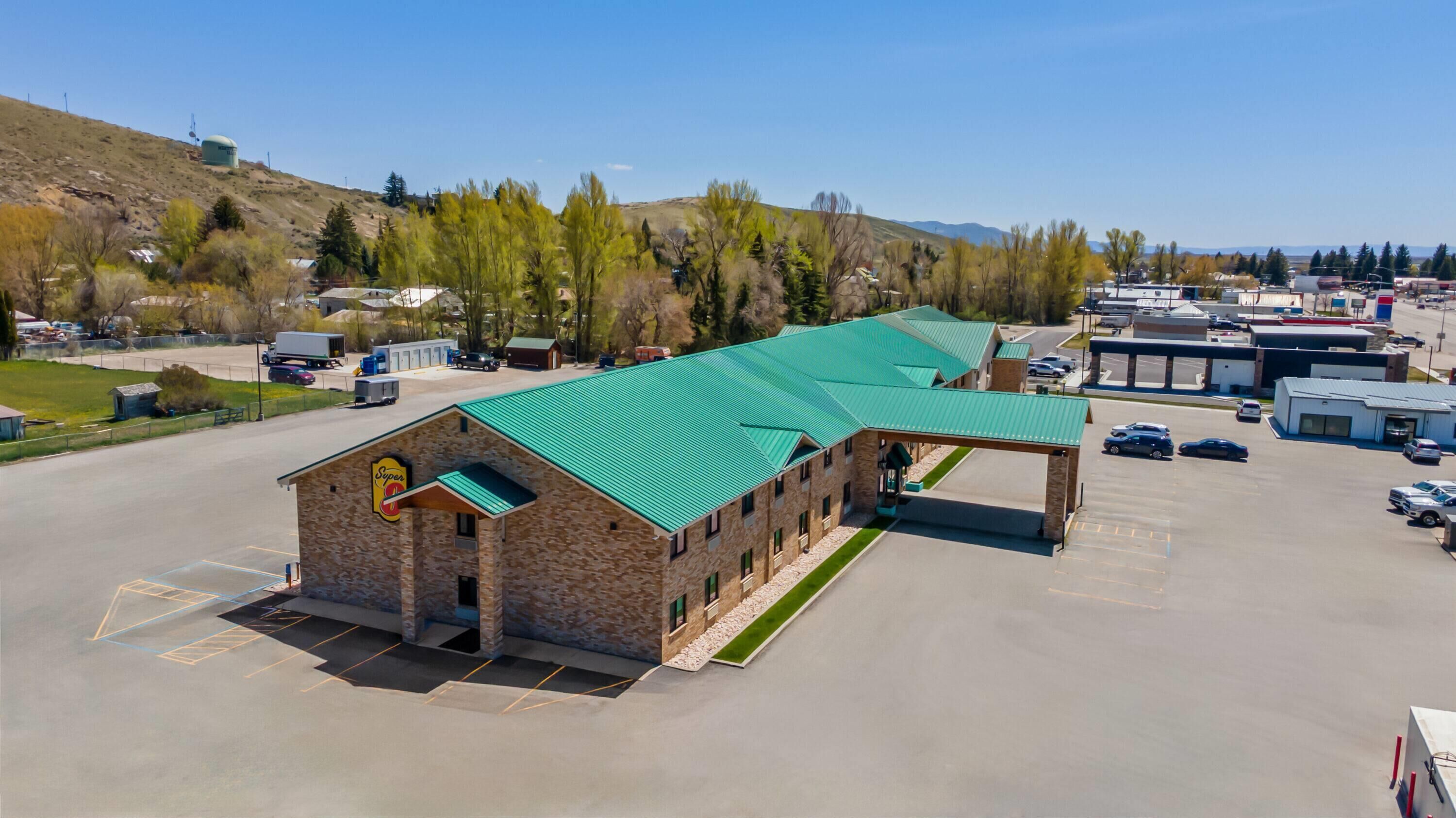A building with a green roof, a Super 8 sign, and a parking lot.
