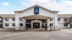 Entrada do hotel Clarion Pointe com uma grande placa, galeria coberta e estacionamento.
