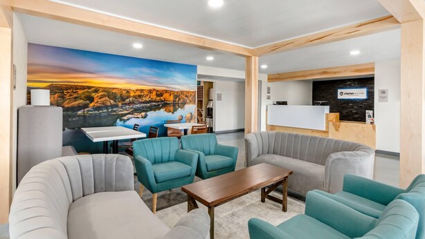 Um lobby moderno com áreas de estar, balcão de recepção e um mural de paisagem.