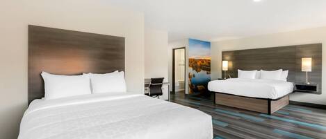A hotel room with two beds, a desk, and a painting on the wall.