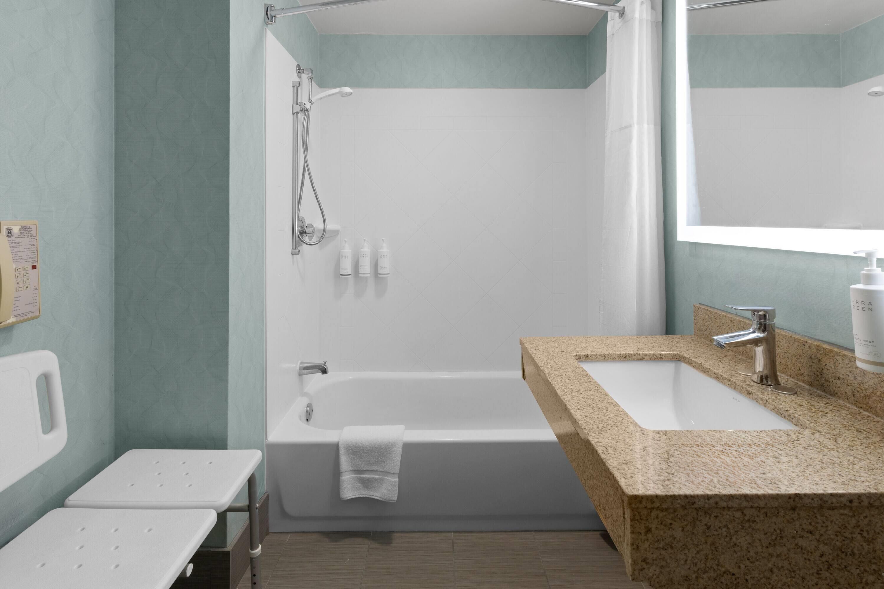 Un baño con bañera, ducha, lavamanos y espejo.