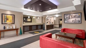A hotel lobby with a reception desk, a red sofa, a coffee table, and a framed picture on the wall. - Super 8 by Wyndham Mars/Cranberry/Pittsburgh Area (Mars)
