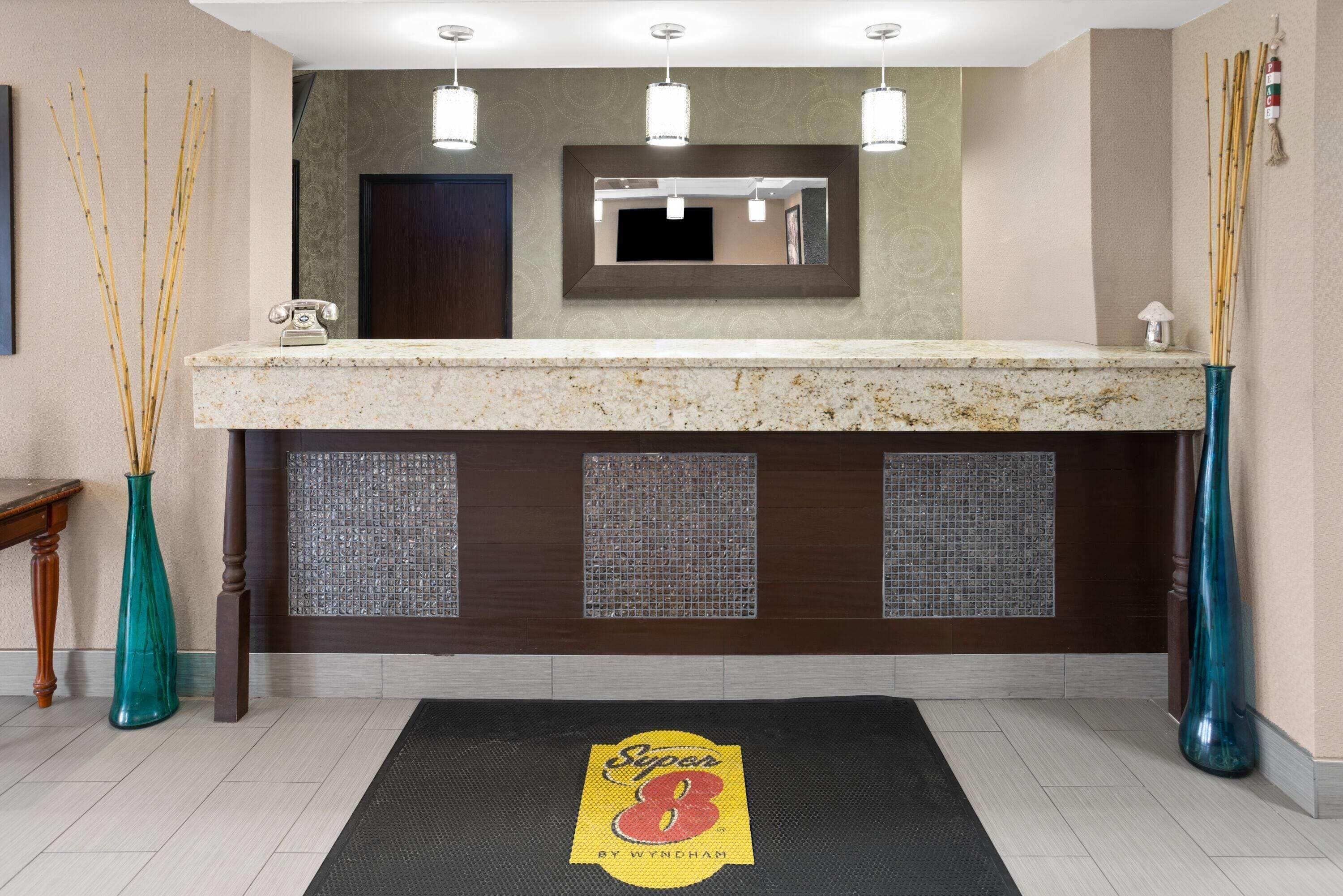 A bathroom with a marble countertop, a mirror, a telephone, and decorative bamboo sticks.