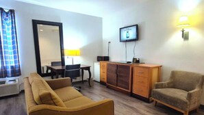A living room with a sofa, armchair, TV, and a desk with a lamp. -  Kings Inn By OYO Calumet Park I-57 (Calumet Park)