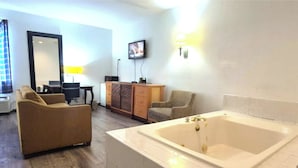 A modern bathroom with a large bathtub, a wooden cabinet, and a seating area with a sofa and armchair. -  Kings Inn By OYO Calumet Park I-57 (Calumet Park)