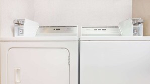 Two white front-loading washing machines in a laundry room. - Super 8 by Wyndham Evansville North (Evansville)
