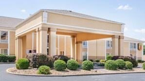 A hotel with a beige exterior, a covered entrance, and neatly trimmed bushes. - Super 8 by Wyndham Evansville North (Evansville)