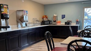 A breakfast bar with a coffee machine, cereal dispenser, and microwave. - Super 8 by Wyndham Evansville North (Evansville)