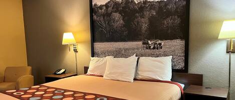 A hotel room with a large bed, two bedside tables, a chair, and a wall-mounted lamp.