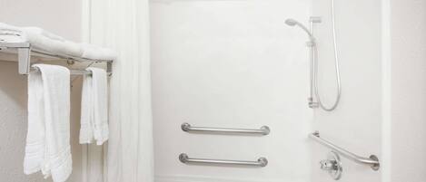 A white bathroom with a shower, grab bars, and a towel rack.
