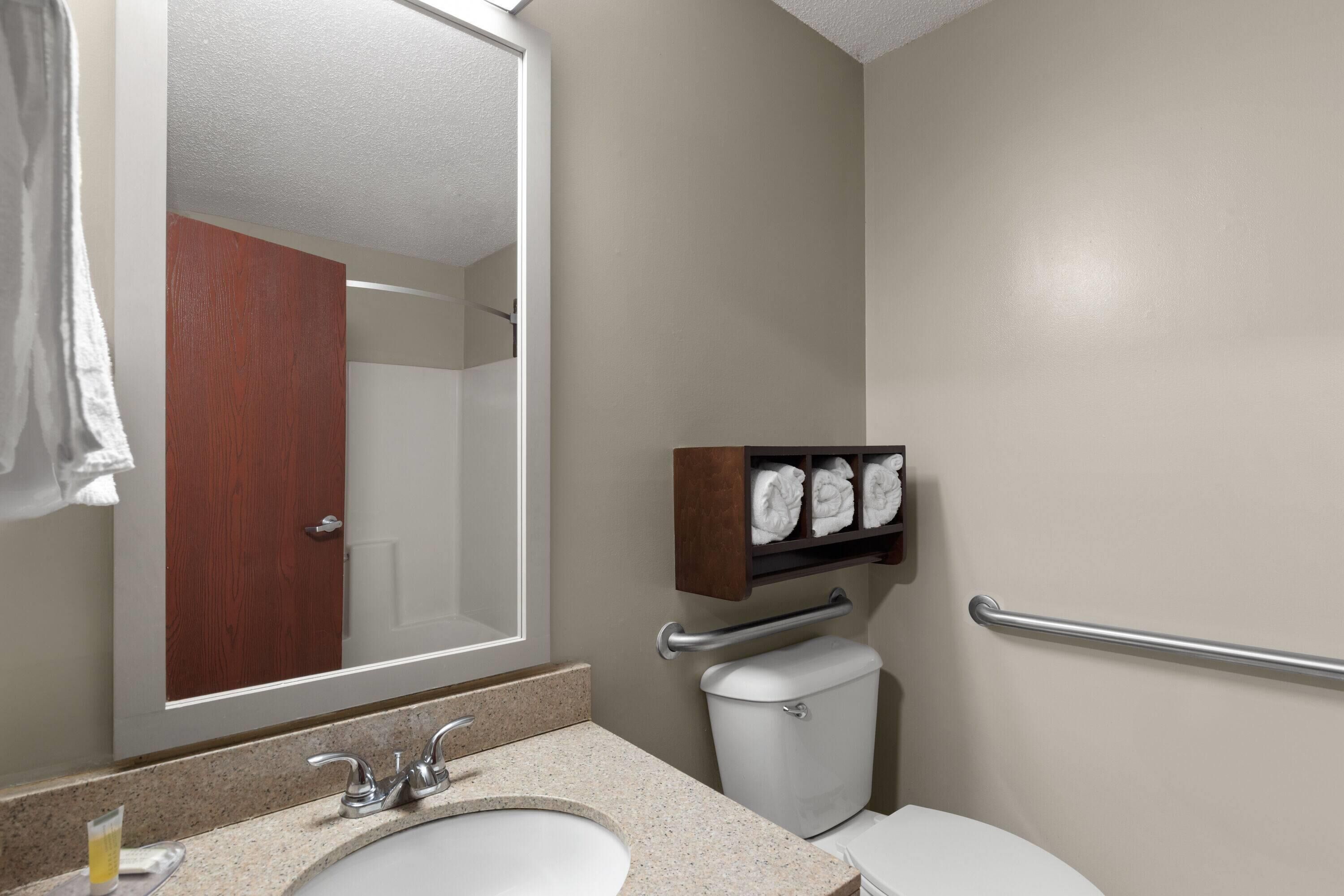 A bathroom with a sink, mirror, toilet, and towel rack.