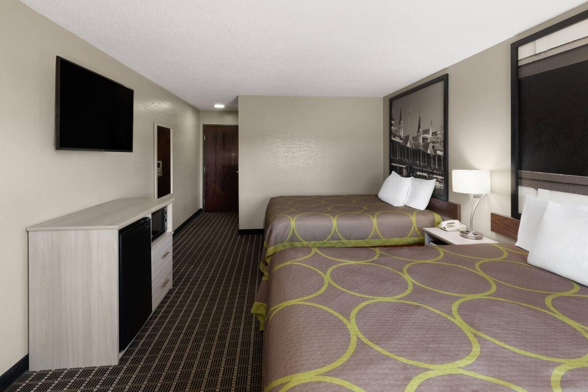 Una habitación de hotel con una cama, un escritorio, un televisor y un cuadro en la pared.