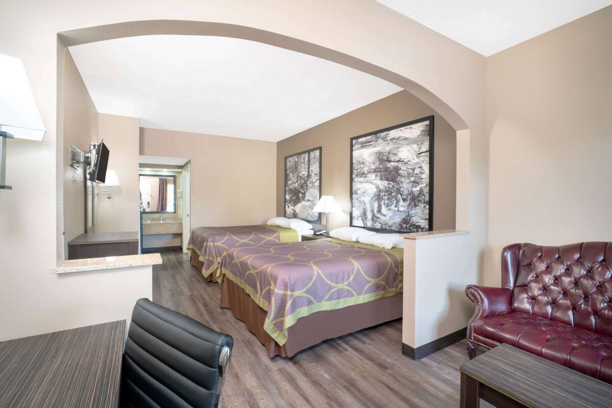 Een hotelkamer met een bed, een leren fauteuil, een bureau en een spiegel.