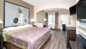 Habitación de hotel con una cama grande, un escritorio, un televisor y un reloj en la pared.