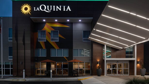 L’entrée d’un hôtel au design moderne, avec un logo solaire bien visible et l’inscription « LA QUINTA ».