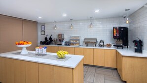 A modern kitchen with a central island, a coffee machine, and a fruit bowl.