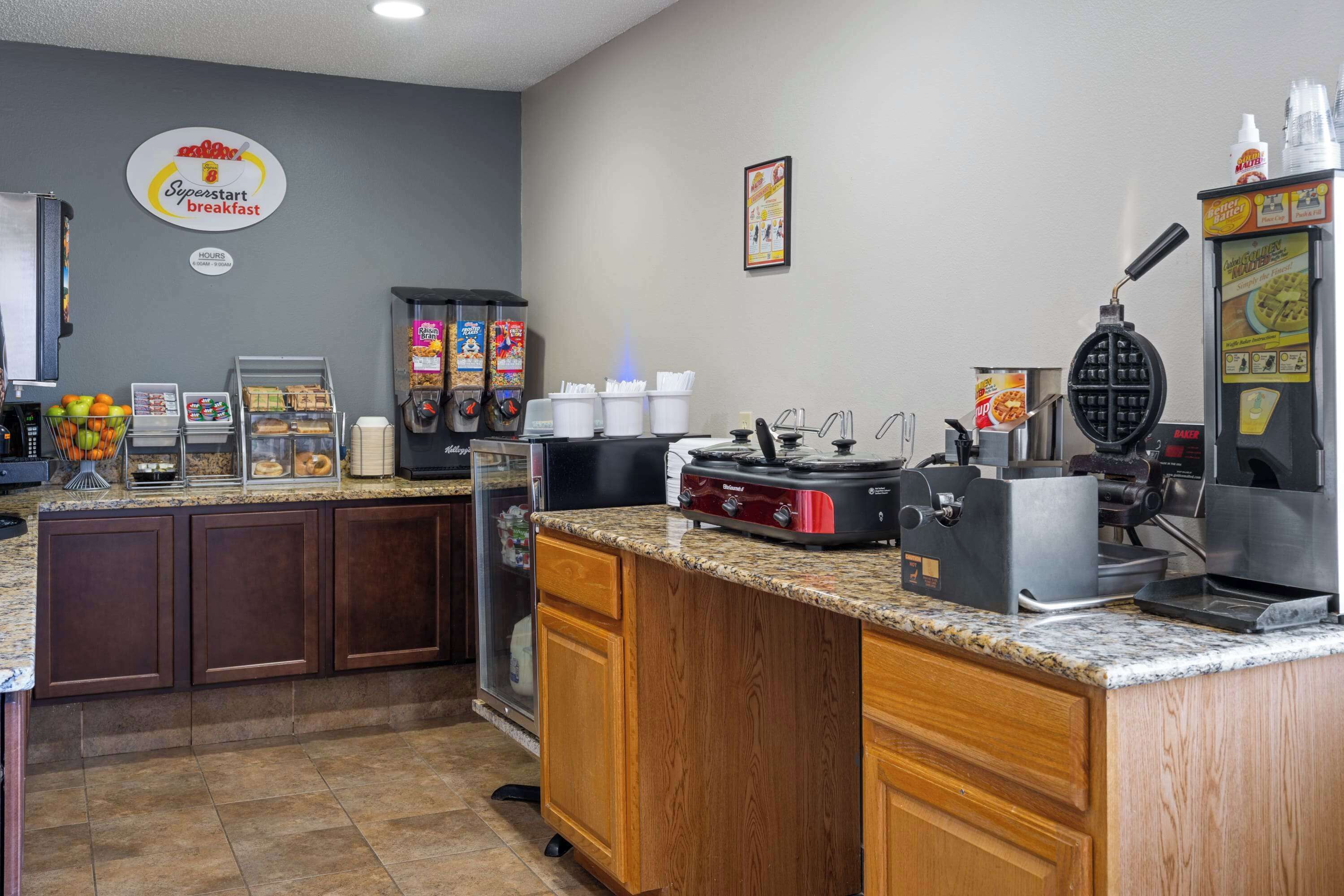 A breakfast area with a waffle maker, coffee machines, and a sign for 'Superstart breakfast'.