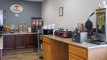 A breakfast area with a waffle maker, coffee machines, and a sign for 'Superstart breakfast'.