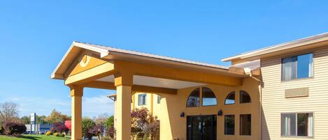 A yellow building with a covered entrance and a parking lot.