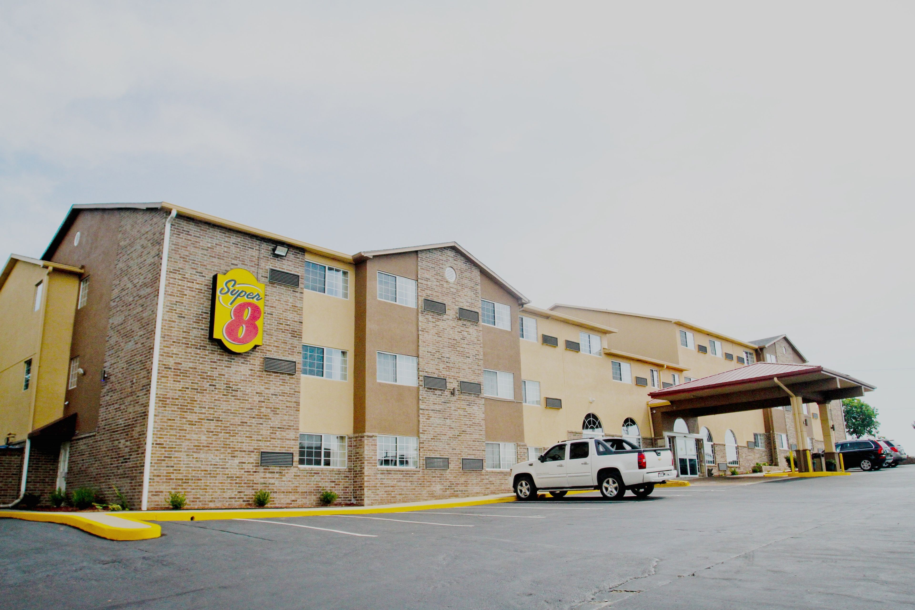 A Super 8 hotel with a brick facade, multiple windows, and a covered parking area.