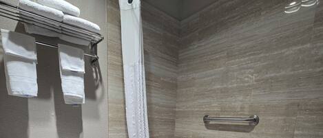 A bathroom with a toilet, a bathtub, a shower curtain, and a towel rack with towels.