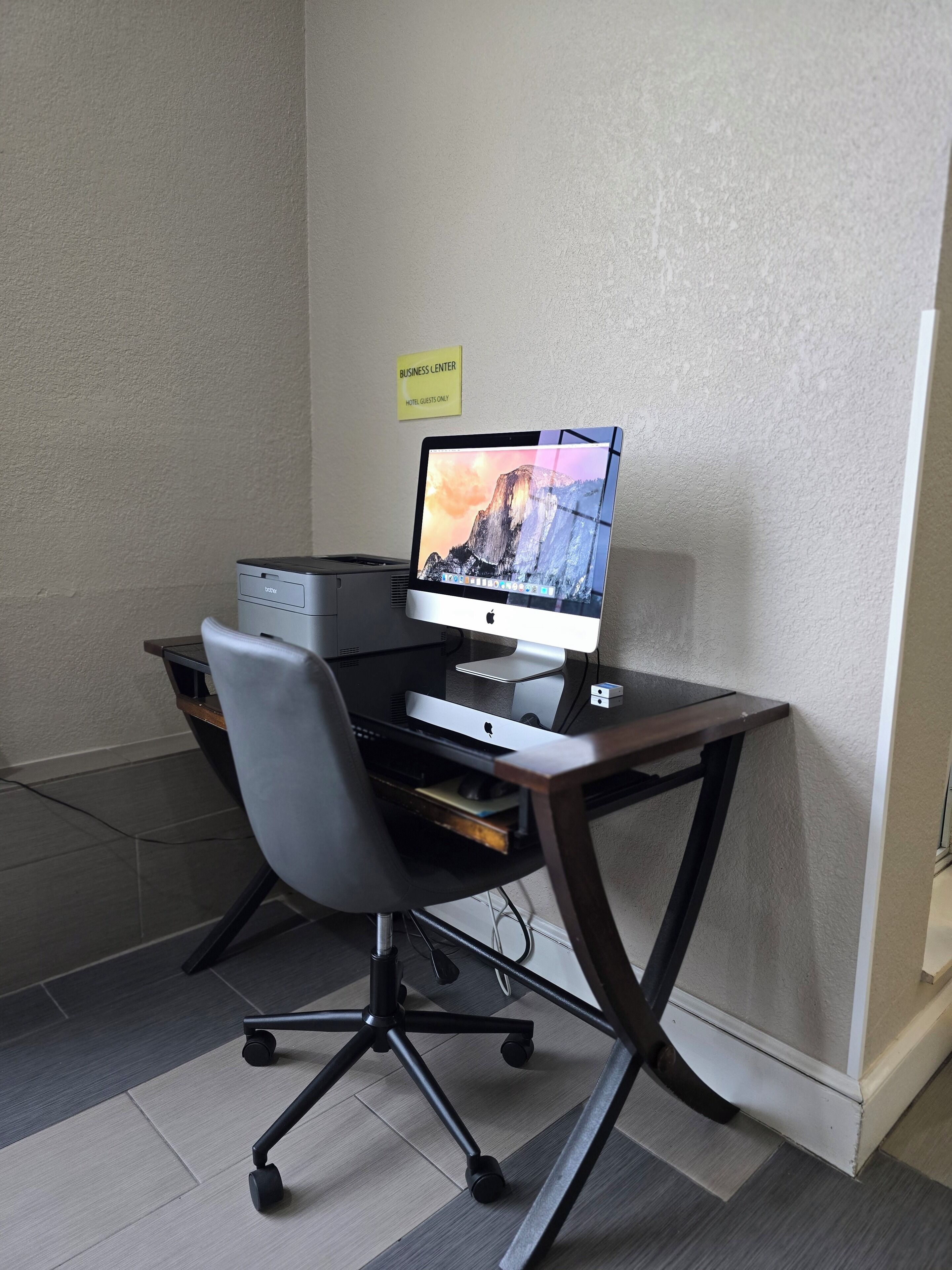 Et hotel-forretningscenter med en stationær computer, en stol og et skilt der angiver, at det kun er for hotelgæster.