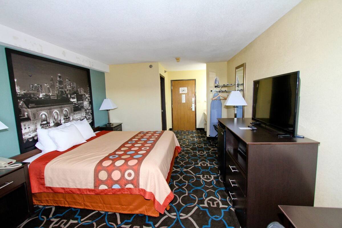 Una habitación de hotel con una cama, televisión, escritorio y espejo.