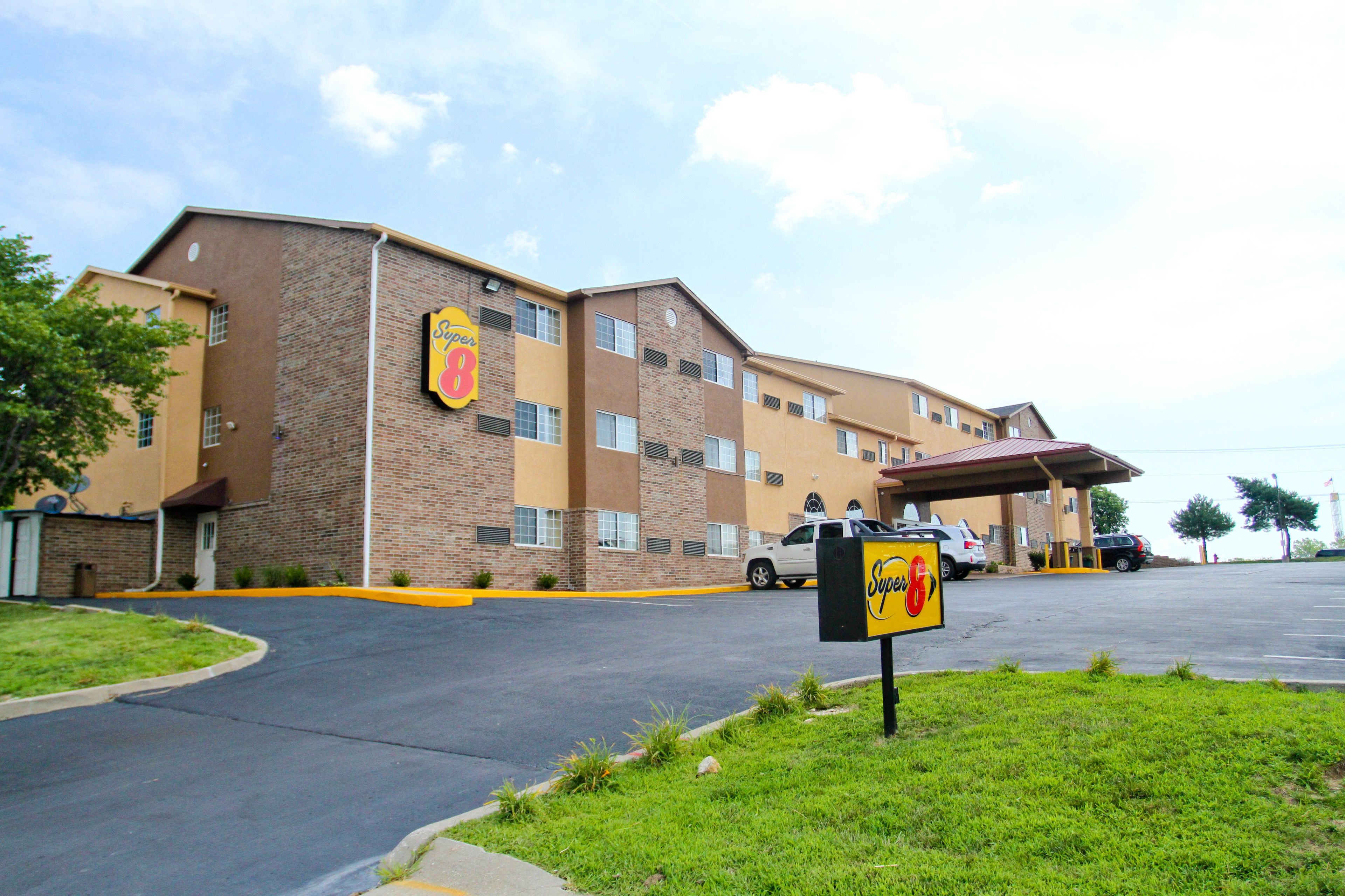 A hotel with a brick facade, multiple windows, and a parking lot.