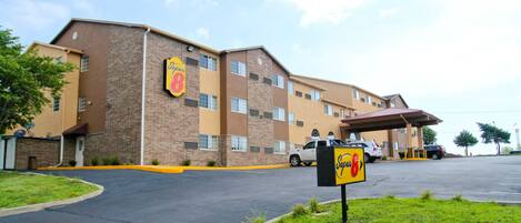 A hotel with a brick facade, multiple windows, and a parking lot.