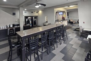A modern kitchen with a bar area, seating, and a staircase leading to another level. - Super 8 by Wyndham Kansas City (Kansas City)