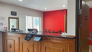 A reception desk with a digital kiosk, a clock, and a red accent wall. - Econo Lodge Chillicothe (Chillicothe)