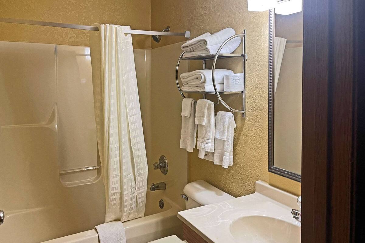 A bathroom with a bathtub, toilet, and a towel rack with towels.