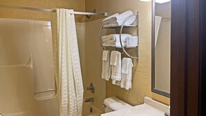 A bathroom with a bathtub, a shower, a toilet, and a sink. There are towels hanging on a rack and a towel on the floor. - Econo Lodge Chillicothe (Chillicothe)