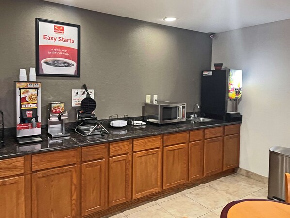 A kitchenette with a microwave, coffee maker, and self-service beverage dispenser.