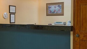 A reception area with a clock, framed notices, and a painting on the wall. - Super 8 by Wyndham Chipley (Chipley)