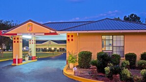 A hotel entrance with a clear sign, a covered parking area, and well-maintained landscaping. - Super 8 by Wyndham Chipley (Chipley)