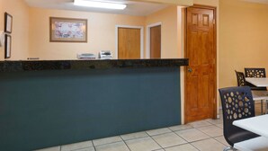 A reception area with a counter, two wooden doors, and a dining area with tables and chairs. - Super 8 by Wyndham Chipley (Chipley)