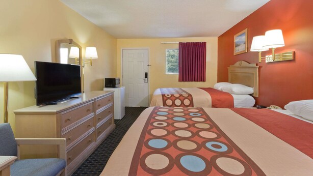 A hotel room with two beds, a television on a dresser, a desk with a lamp, and a door. - Super 8 by Wyndham Chipley (Chipley)