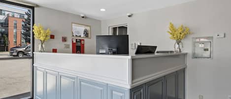 A reception area with a white counter, a black television, and two vases with yellow flowers.