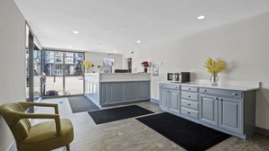 A modern kitchen with grey cabinetry, a black countertop, and a yellow chair. - The Inn on Arsenal (Watertown)