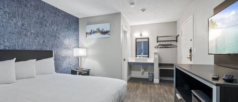 Une chambre d’hôtel avec un grand lit, un bureau avec un ordinateur, une télévision et une salle de bain avec douche et toilettes.