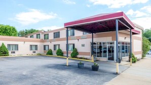 A modern building with a covered entrance, multiple windows, and a parking lot. - The Inn on Arsenal (Watertown)